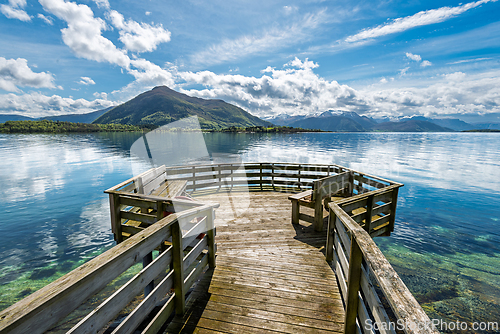 Image of Scenic wooden dock overlooking a tranquil fjord surrounded by mo