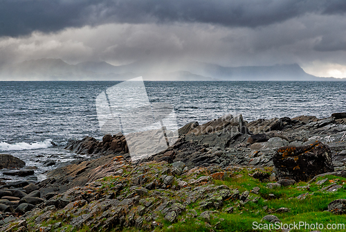 Image of Dramatic coastal landscape with rocky shore and stormy clouds ov
