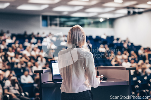 Image of Female speaker giving a talk on corporate business conference. Unrecognizable people in audience at conference hall. Business and Entrepreneurship event.