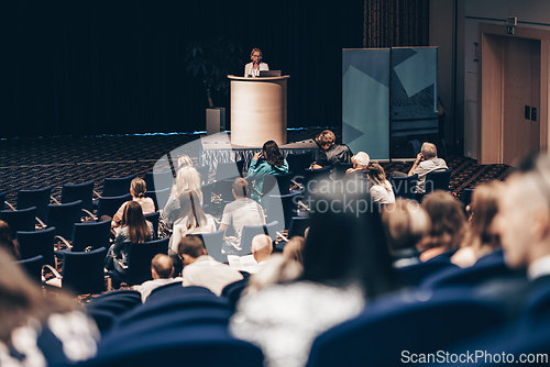 Image of Female speaker giving a talk on corporate business conference. Unrecognizable people in audience at conference hall. Business and Entrepreneurship event.