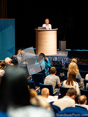 Image of Female speaker giving a talk on corporate business conference. Unrecognizable people in audience at conference hall. Business and Entrepreneurship event.