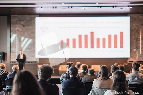 Image of Speaker giving a talk in conference hall at business event. Rear view of unrecognizable people in audience at the conference hall. Business and entrepreneurship concept.