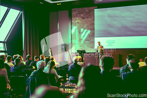 Image of Speaker giving a talk in conference hall at business event. Rear view of unrecognizable people in audience at the conference hall. Business and entrepreneurship concept.