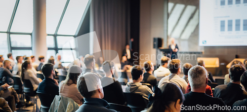 Image of Speaker giving a talk in conference hall at business event. Rear view of unrecognizable people in audience at the conference hall. Business and entrepreneurship concept.