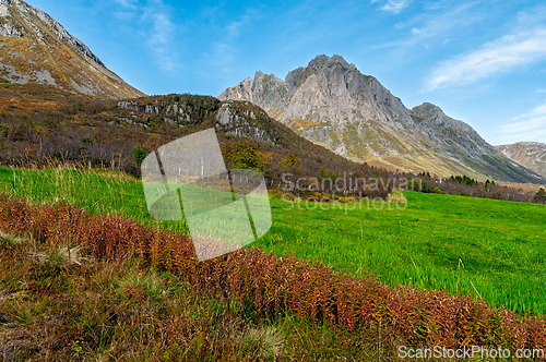 Image of Majestic mountains rise above a lush green valley under a clear 