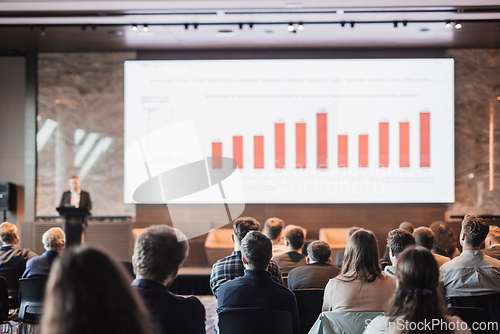 Image of Speaker giving a talk in conference hall at business event. Rear view of unrecognizable people in audience at the conference hall. Business and entrepreneurship concept.