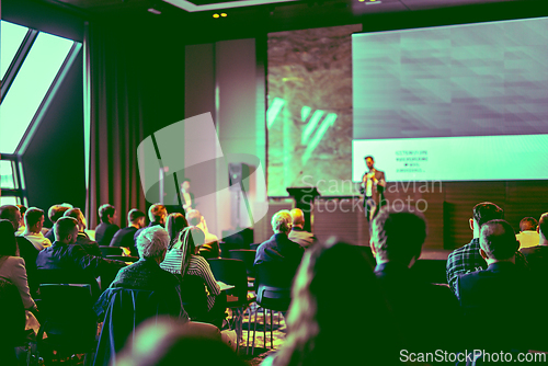 Image of Speaker giving a talk in conference hall at business event. Rear view of unrecognizable people in audience at the conference hall. Business and entrepreneurship concept.