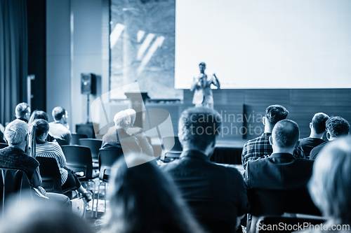 Image of Speaker giving a talk in conference hall at business event. Business and entrepreneurship concept. Blue toned black and white image.
