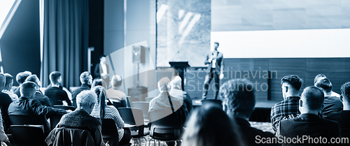 Image of Speaker giving a talk in conference hall at business event. Business and entrepreneurship concept. Blue toned black and white image.