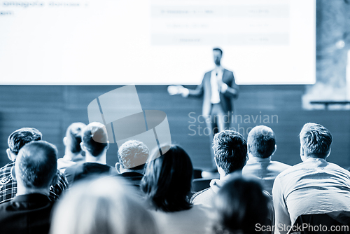 Image of Speaker giving a talk in conference hall at business event. Business and entrepreneurship concept. Blue toned black and white image.