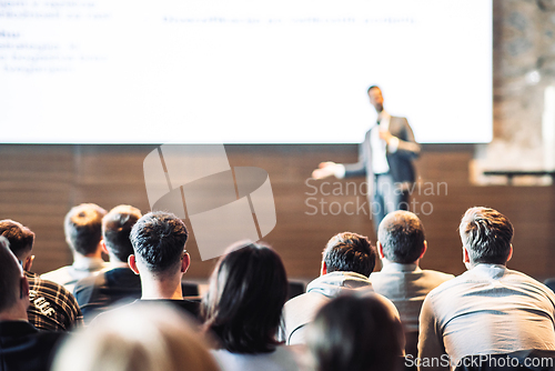 Image of Speaker giving a talk in conference hall at business event. Rear view of unrecognizable people in audience at the conference hall. Business and entrepreneurship concept.