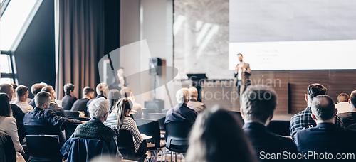 Image of Speaker giving a talk in conference hall at business event. Rear view of unrecognizable people in audience at the conference hall. Business and entrepreneurship concept.