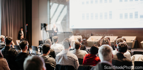 Image of Female speaker giving a talk on corporate business conference. Unrecognizable people in audience at conference hall. Business and Entrepreneurship event.