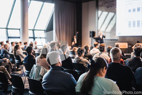 Image of Speaker giving a talk in conference hall at business event. Rear view of unrecognizable people in audience at the conference hall. Business and entrepreneurship concept.