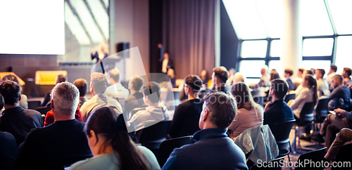 Image of Speaker giving a talk in conference hall at business event. Rear view of unrecognizable people in audience at the conference hall. Business and entrepreneurship concept.