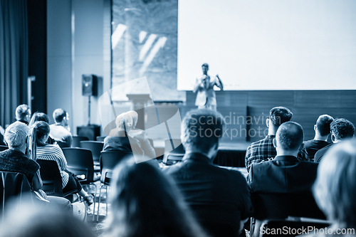 Image of Speaker giving a talk in conference hall at business event. Business and entrepreneurship concept. Blue toned black and white image.