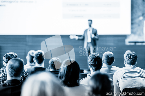 Image of Speaker giving a talk in conference hall at business event. Business and entrepreneurship concept. Blue toned black and white image.