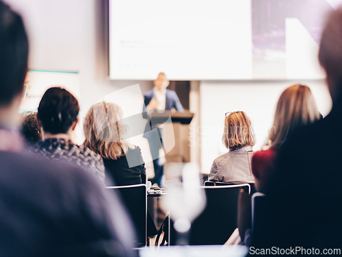 Image of Speaker giving a talk in conference hall at business event. Rear view of unrecognizable people in audience at the conference hall. Business and entrepreneurship concept.