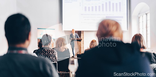 Image of Speaker giving a talk in conference hall at business event. Rear view of unrecognizable people in audience at the conference hall. Business and entrepreneurship concept.