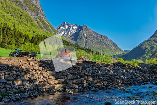 Image of Construction work progresses along a riverbank in a picturesque 