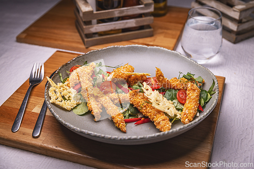 Image of Breaded chicken strips topping fresh green salad