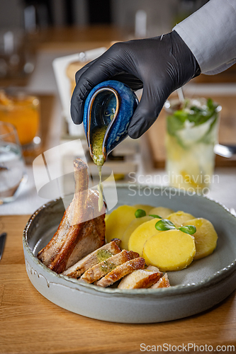 Image of Chef pouring sauce on grilled pork ribs