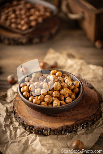 Image of Shelled hazelnuts in a bowl placed on a wooden board