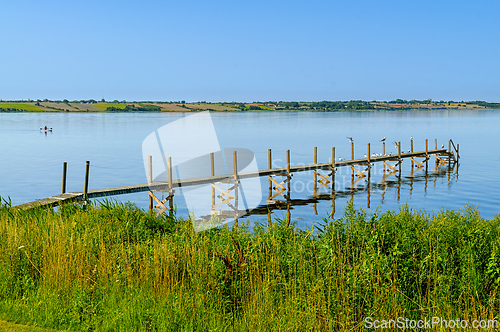Image of Peaceful dock extending into calm waters surrounded by lush gree