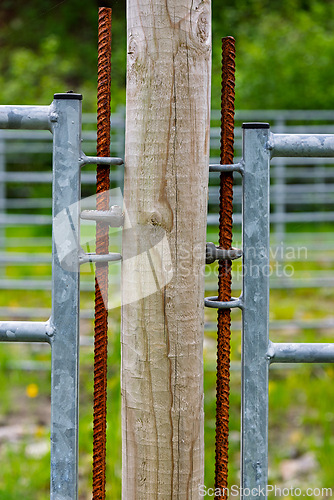 Image of Rusty gate hinges attached to a wooden post in a rural area duri