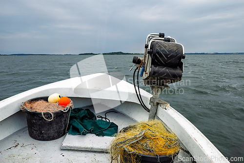 Image of Fishing boat with gear navigating calm waters near shoreline in 