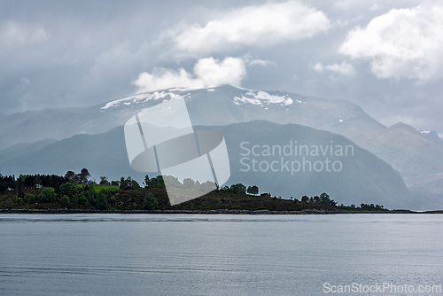 Image of Mountains rise majestically behind a calm lake in Norway during 