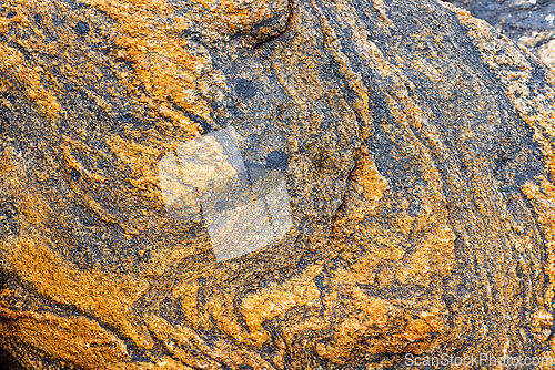 Image of Vivid orange and black textured rock formation found along a coa