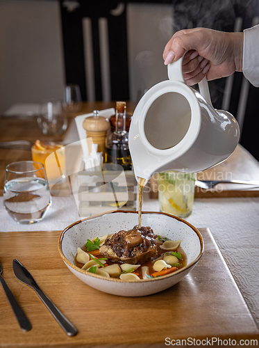 Image of Waiter pouring broth
