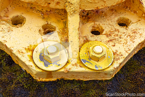 Image of Rusty yellow bolts and nuts on weathered metal surface in an ind