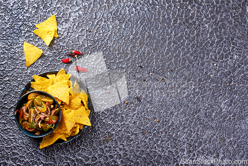 Image of Single big black plate of yellow corn tortilla nachos chips with salsa sauce