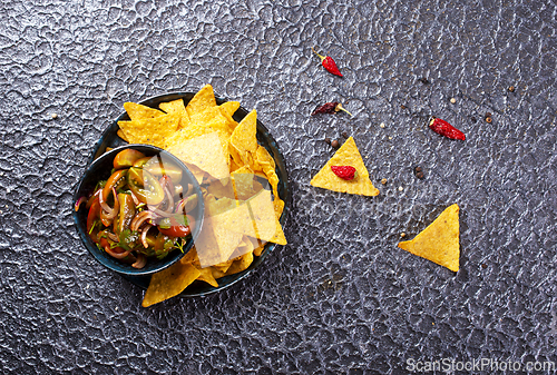 Image of Single big black plate of yellow corn tortilla nachos chips with salsa sauce