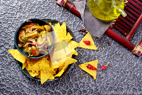 Image of Single big black plate of yellow corn tortilla nachos chips with salsa sauce