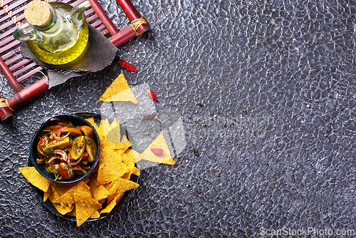Image of Single big black plate of yellow corn tortilla nachos chips with salsa sauce