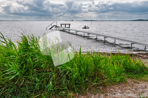 Image of Serene sea view with a wooden dock and cloudy skies during a cal