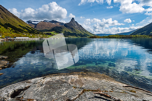 Image of Scenic view of tranquil lake reflecting mountains and clouds dur
