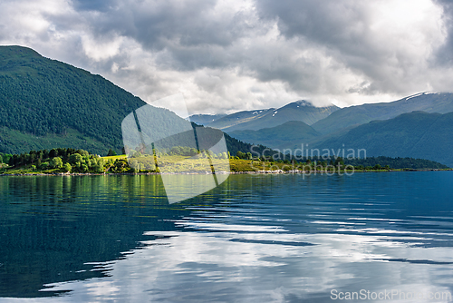 Image of Serene landscape of mountains and calm waters in the early morni