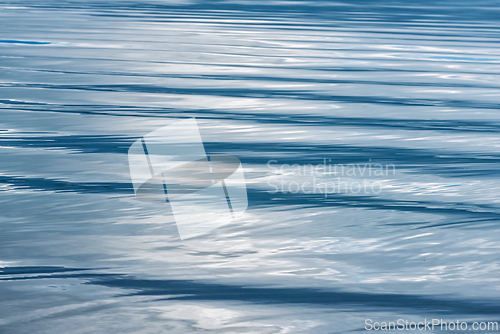 Image of Rippling blue water surface reflecting light during midday at a 