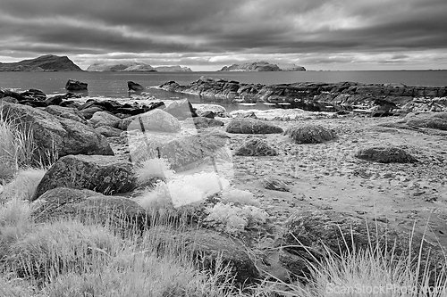 Image of Infrared view of rocky shoreline and islands under dramatic clou