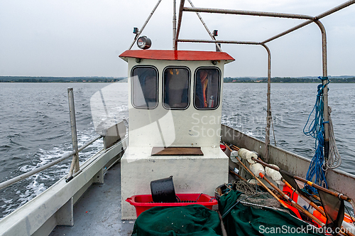 Image of Fishing boat navigating calm waters on an overcast day near a tr