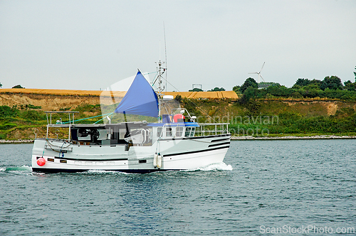 Image of Fishing boat with blue sail navigating through calm waters near 