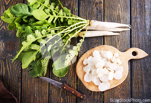 Image of White radish and knife on wooden board
