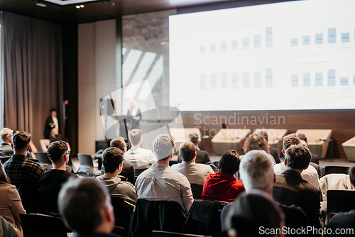 Image of Female speaker giving a talk on corporate business conference. Unrecognizable people in audience at conference hall. Business and Entrepreneurship event.