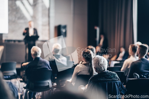 Image of Speaker giving a talk in conference hall at business event. Rear view of unrecognizable people in audience at the conference hall. Business and entrepreneurship concept.