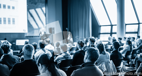 Image of Speaker giving a talk in conference hall at business event. Business and entrepreneurship concept. Blue toned black and white image.