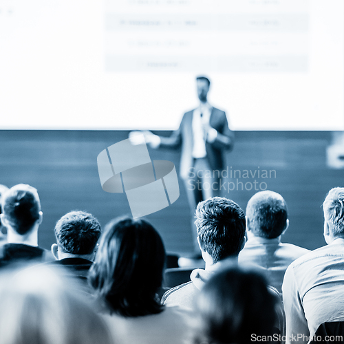 Image of Speaker giving a talk in conference hall at business event. Business and entrepreneurship concept. Blue toned black and white image.